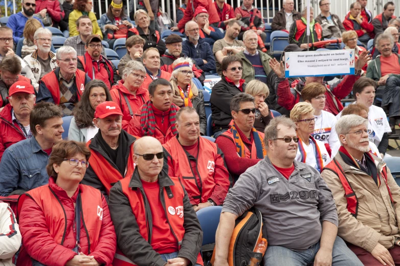 a crowd in red jackets and sunglasses sitting together in an arena