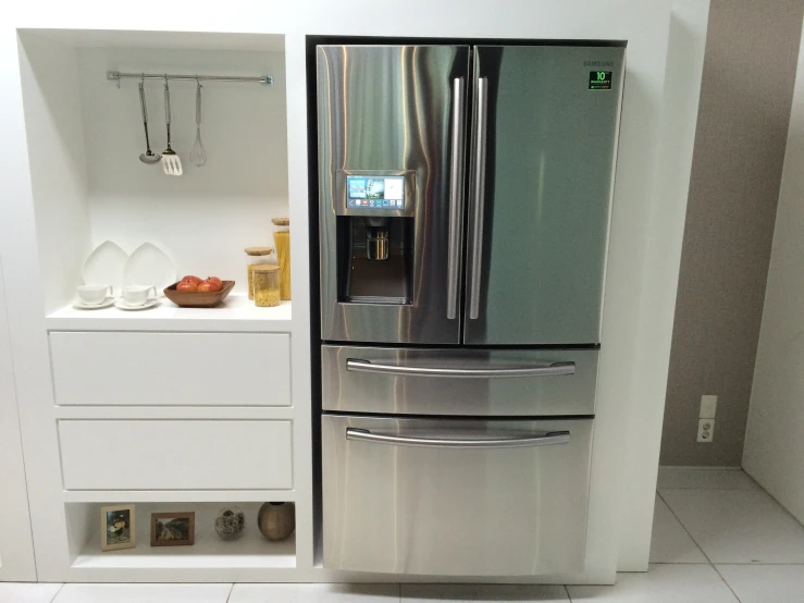 a stainless steel refrigerator is next to some white cupboards