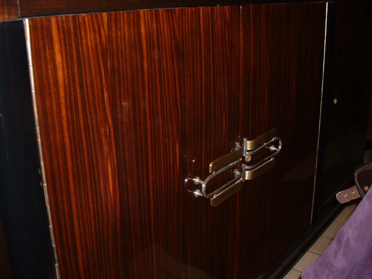 the door handle is on a modern looking wood paneled cabinet