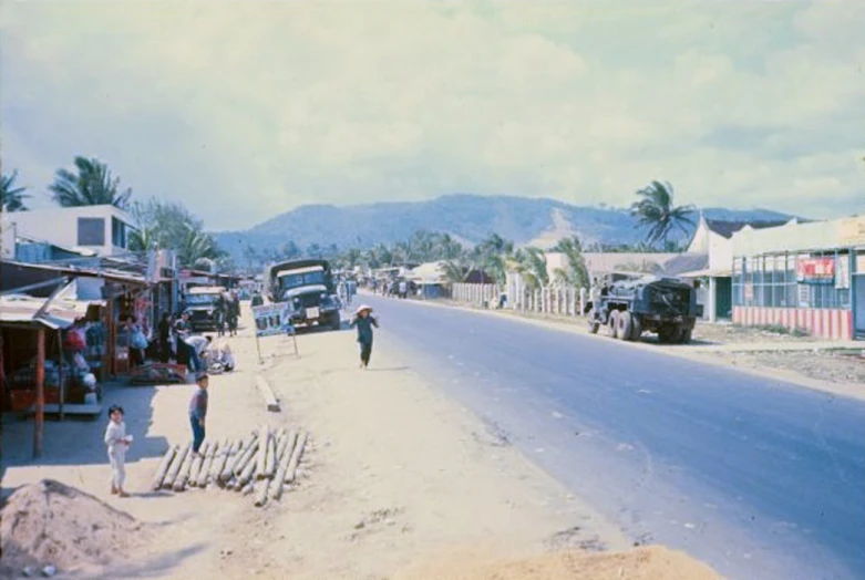 a city street in the 1950's with people, cars and a truck