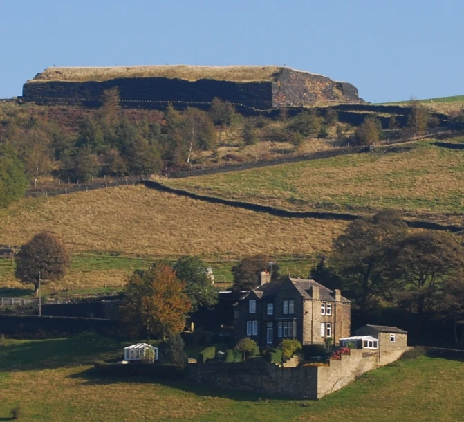 a house sitting on the side of a grassy hillside