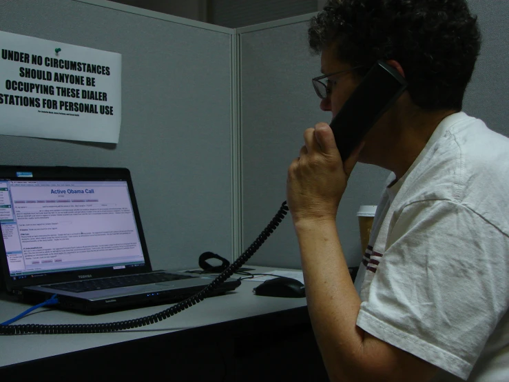 a man sitting at a desk talking on a cell phone