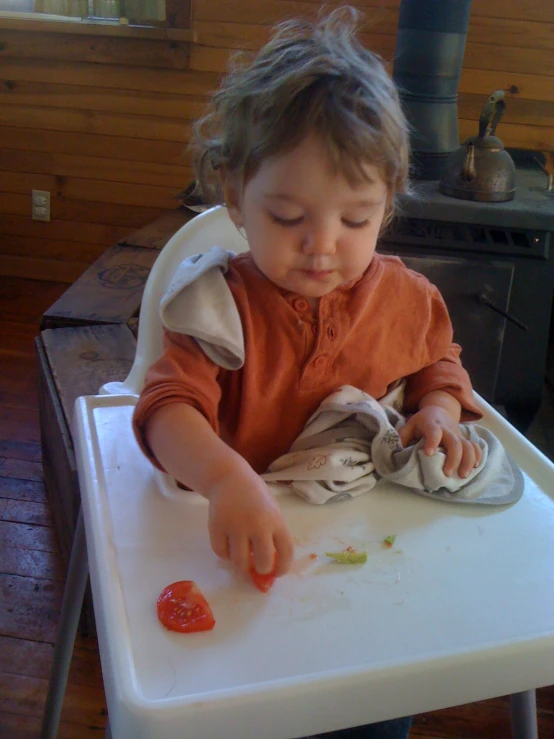 an infant plays with an object while eating it from the high chair