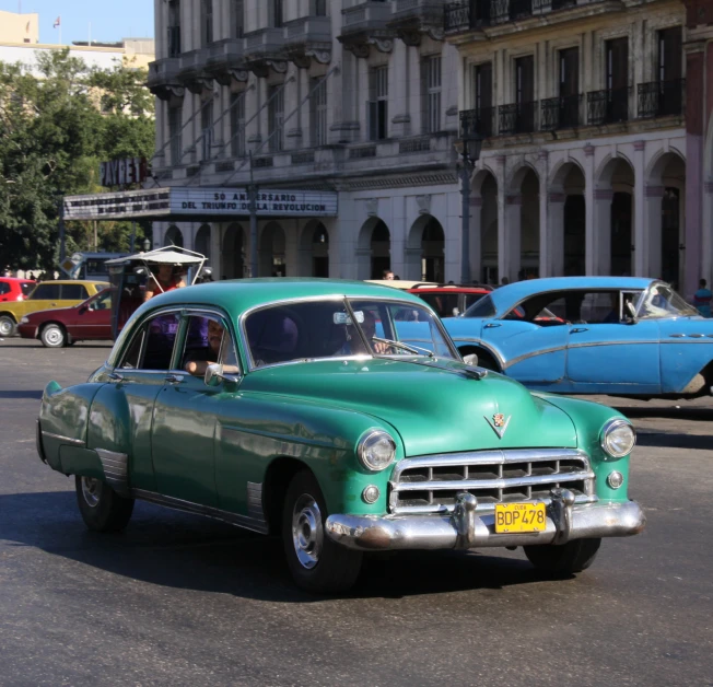 two antique cars driving down the street next to buildings