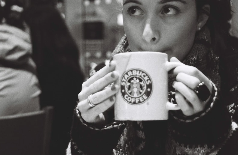 a woman with her face looking in the mirror while holding a starbucks mug