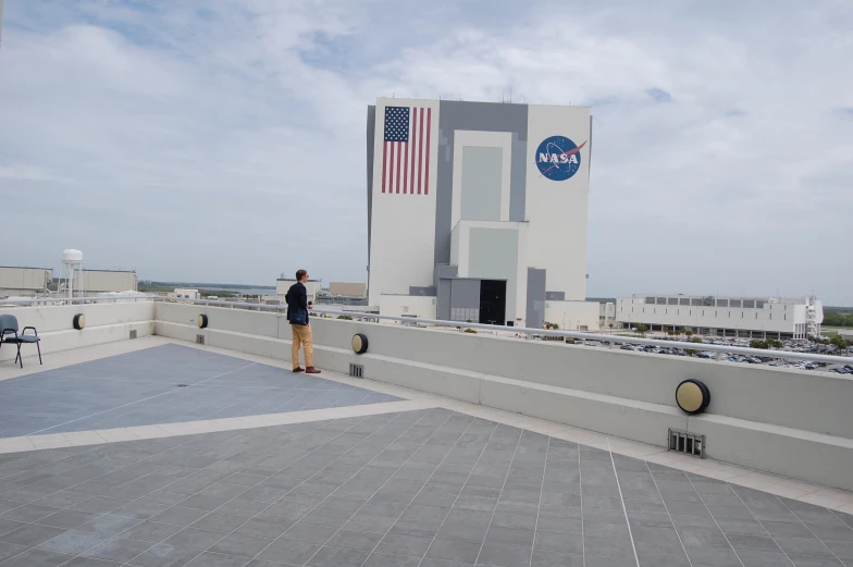 a man standing on the roof looking up at the space shuttle in the background