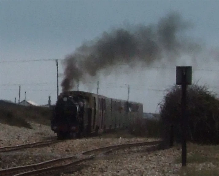 a train is smoking up steam while traveling on tracks