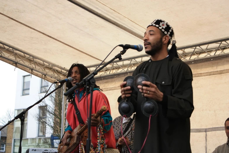 a man with dreadlocks sings into microphones and an instrument