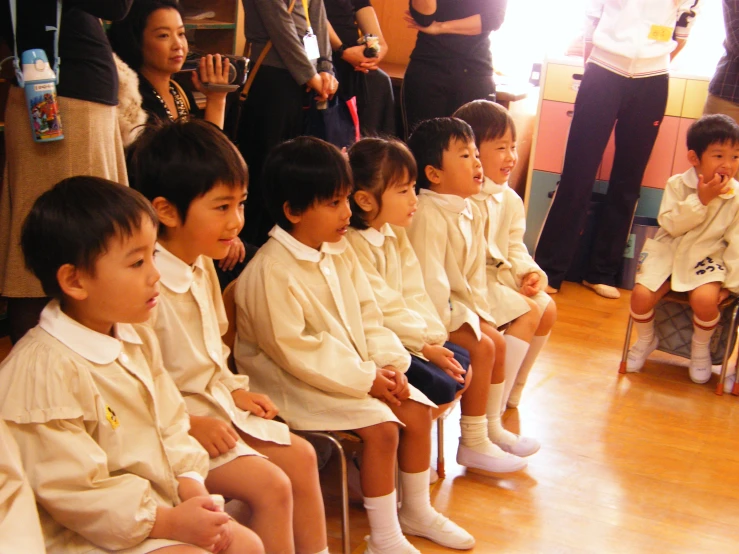 children are sitting on benches in front of a crowd