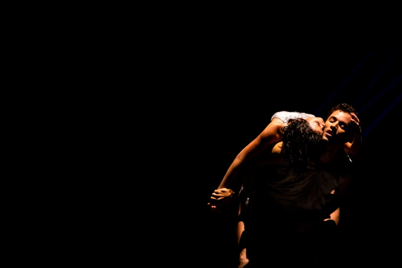 a young couple emcing on stage in the dark