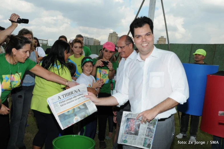 a man holds up the news for people to watch