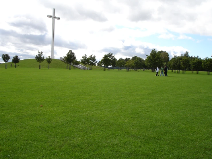 a green grassy field filled with people flying a kite