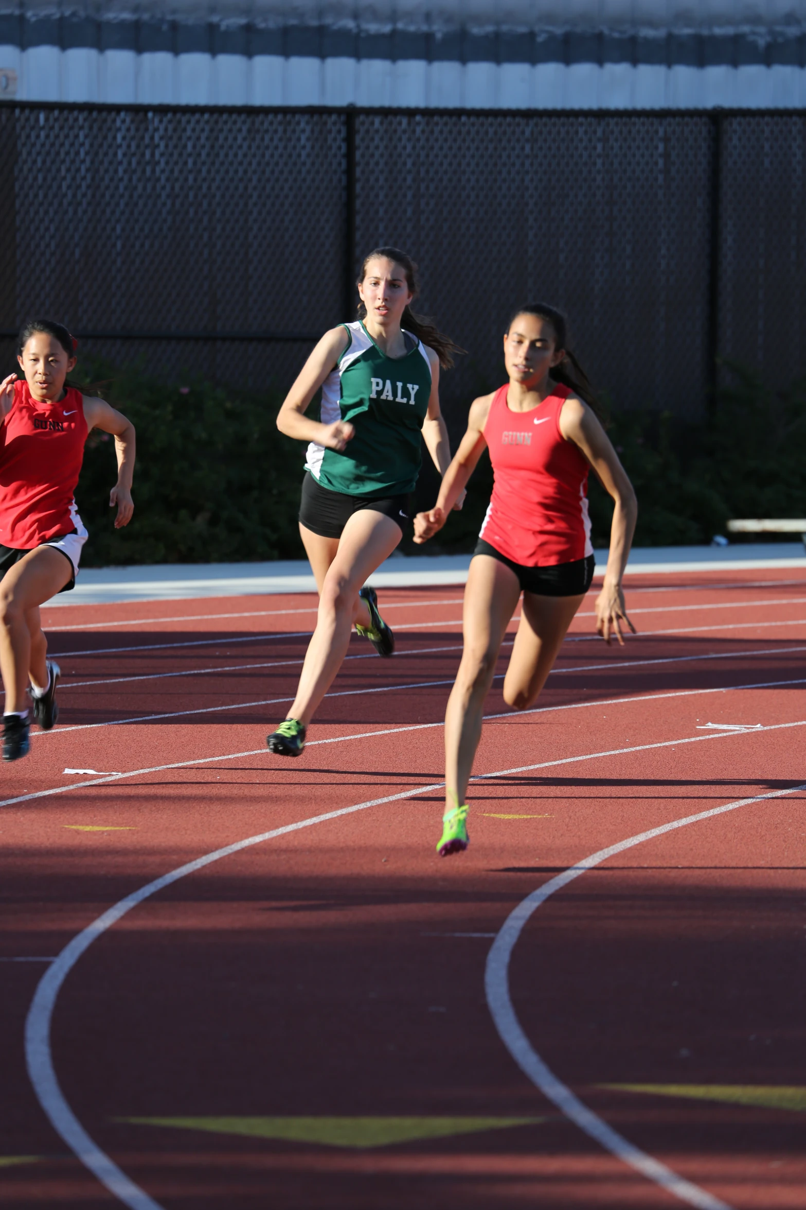 three girls racing on a track with one running away