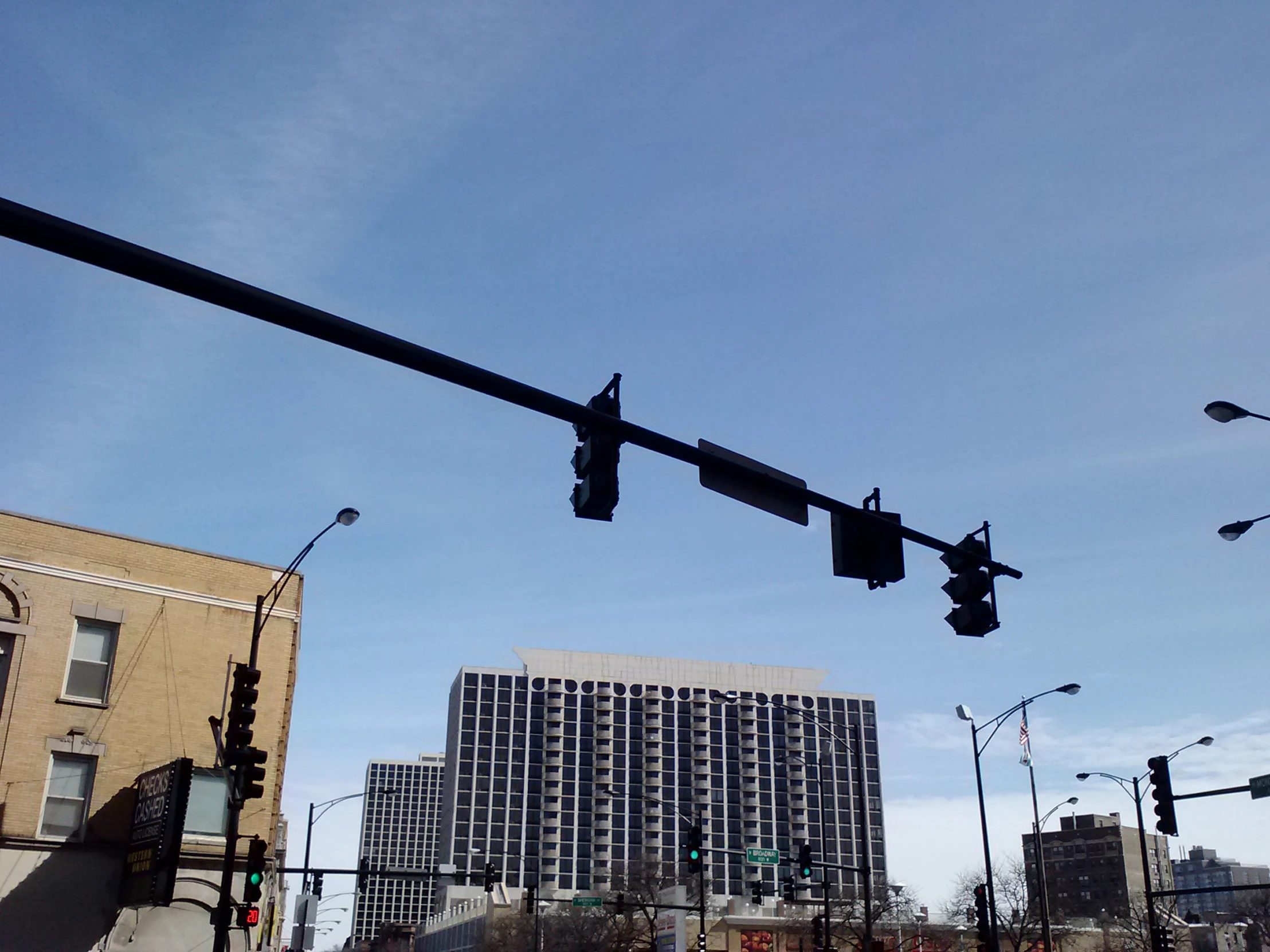 a stop sign above the street as buildings line the other side