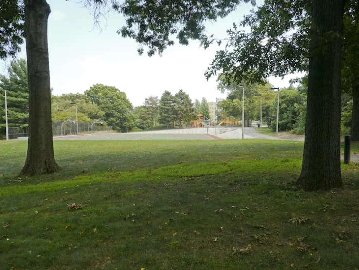 a park with a tennis court surrounded by green grass