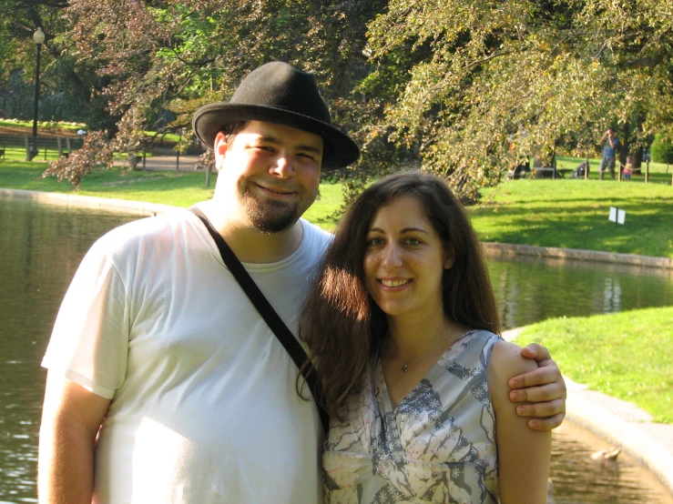 a couple poses together by the water in the park