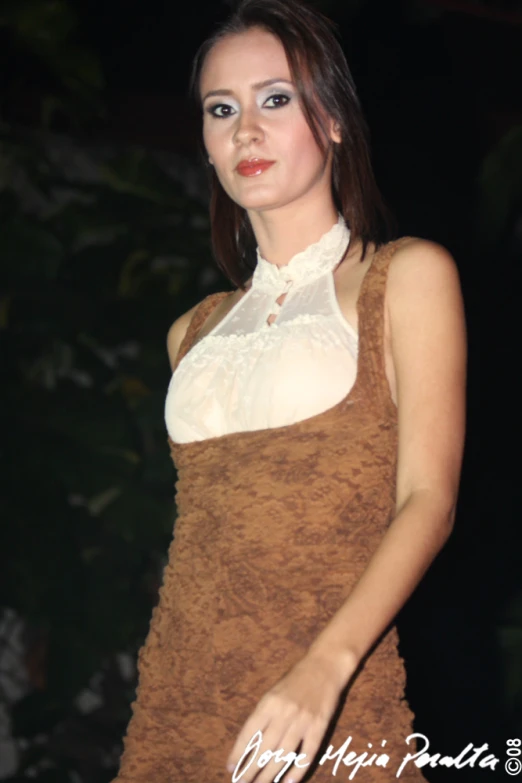 a woman dressed in a brown costume is standing in the dark