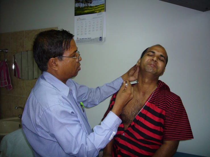 a person in a blue and white shirt putting another man's shirt on his neck