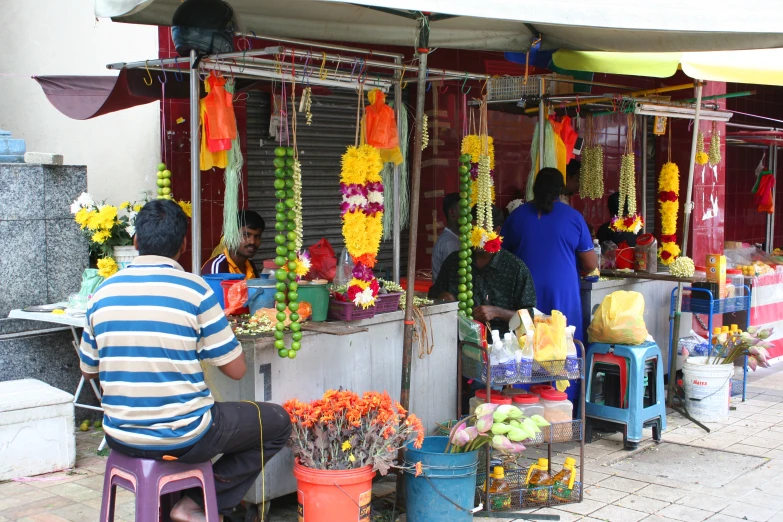 the woman are looking at the stalls with flowers