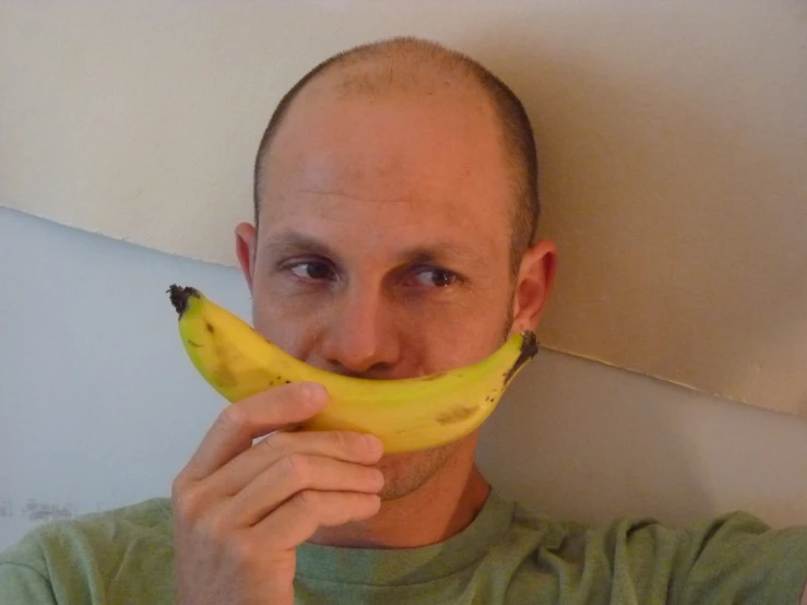 man holding banana in front of his face