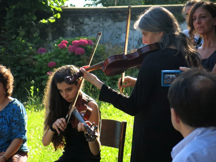 a group of women playing violin in a park