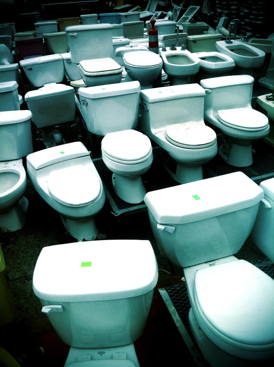 a lot of white toilets stacked up together