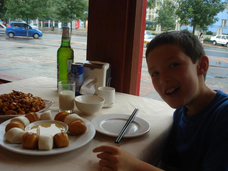 a  at a table with several donuts, rolls and drinks