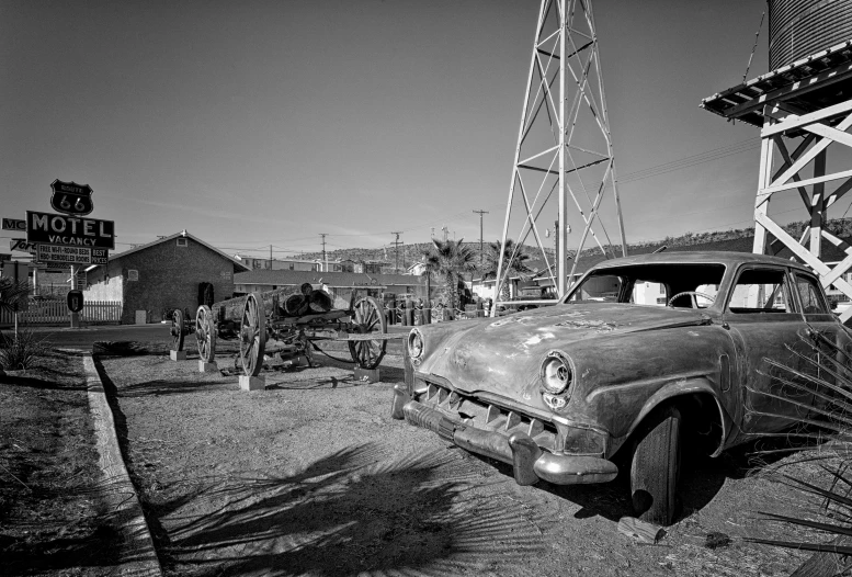 the old car is sitting by the windmill