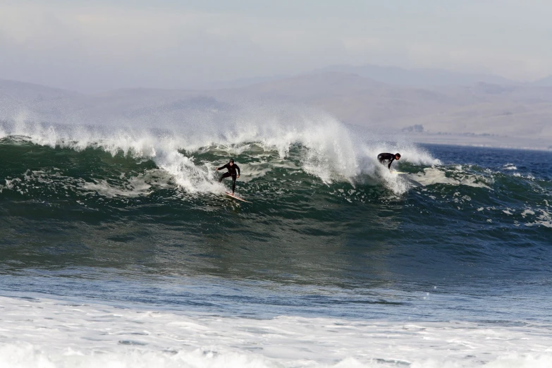 two surfers riding the crest of a very big wave