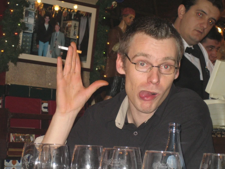 a man with glasses sitting in front of many bottles and glass