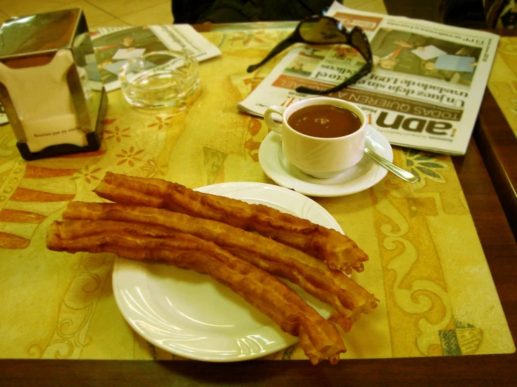 a plate of fried eggs with dipping sauce next to coffee