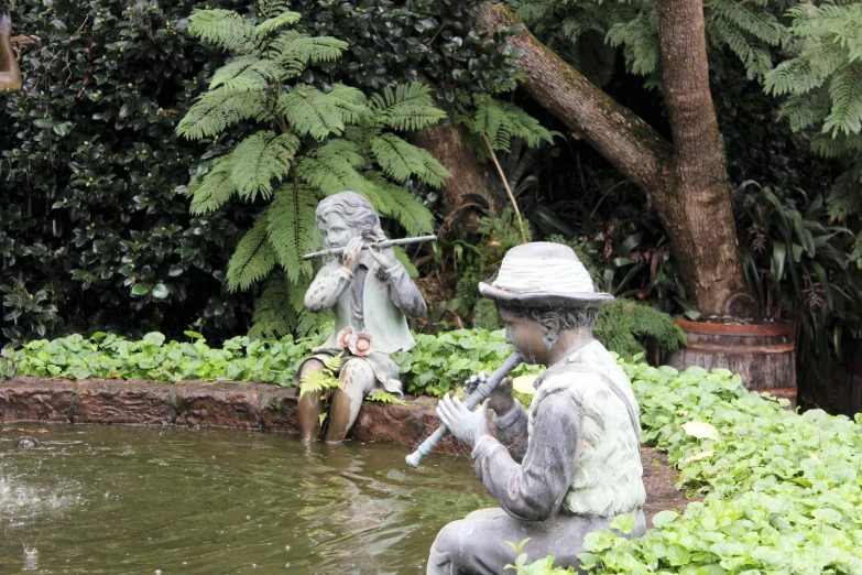 statue of two people sitting near water drinking from each other