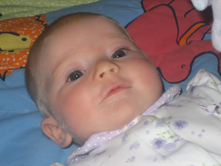 a baby in blue sheets with teddy bears on the covers