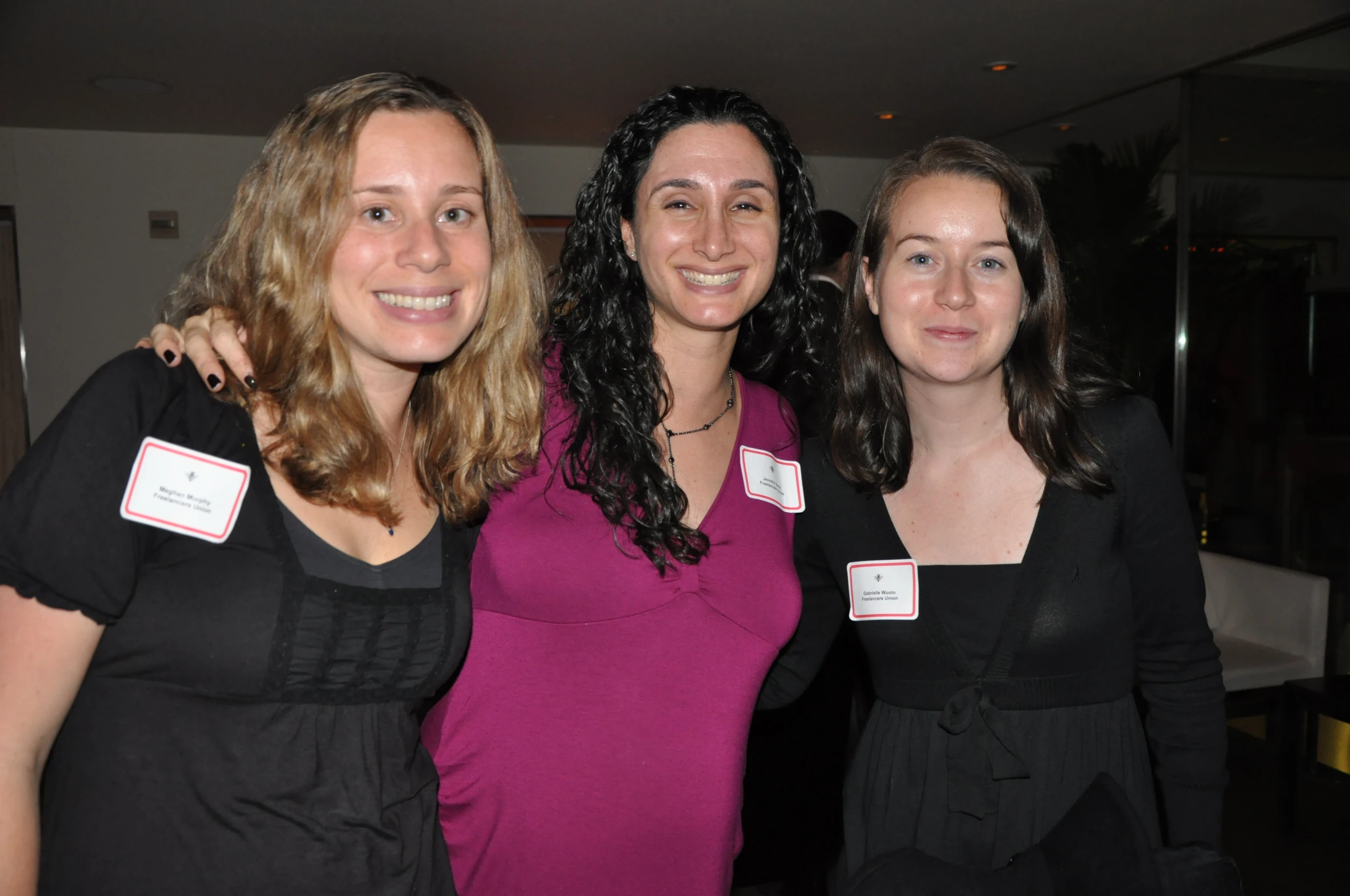 three women smiling for a po at an event