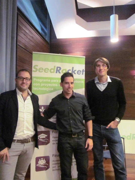 three men standing next to each other in front of a sign