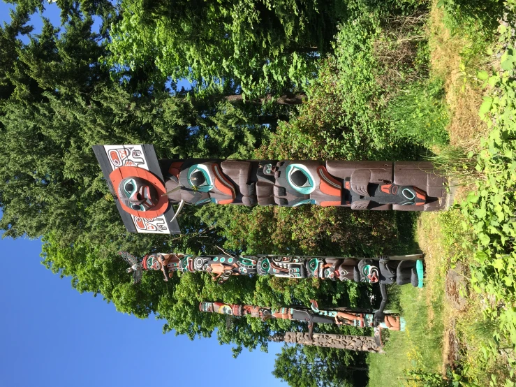 three colorful totem poles with carved heads in a field
