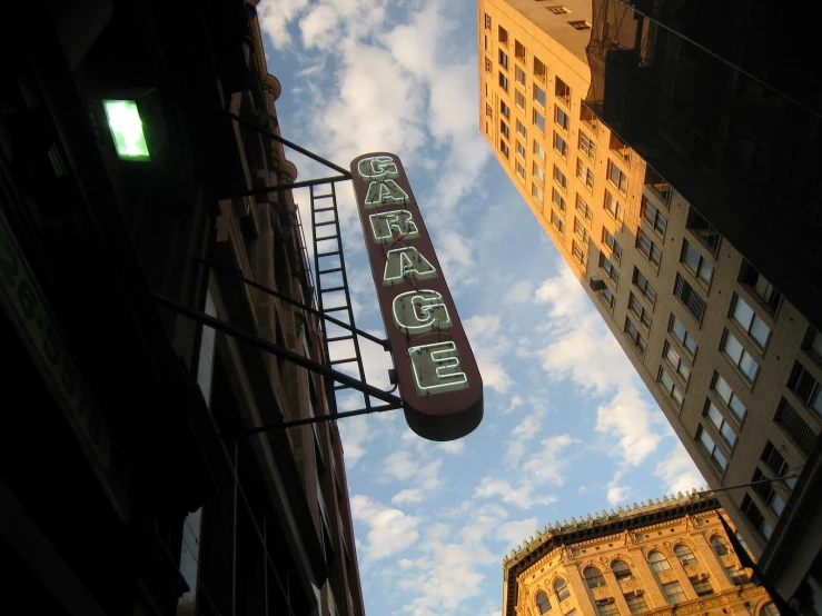 a neon sign above some building against the sky