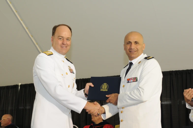 two naval officers holding a plaque while receiving another award