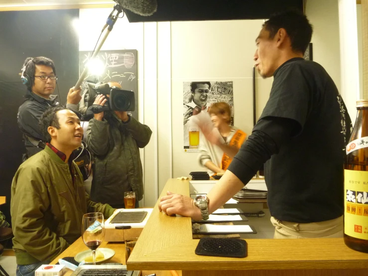 man in front of group on wooden desk taking pictures