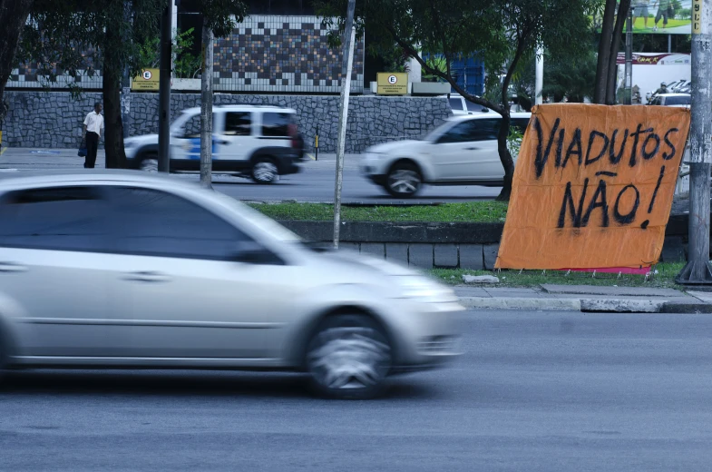 an orange sign that reads nautitass no and is placed on a street corner