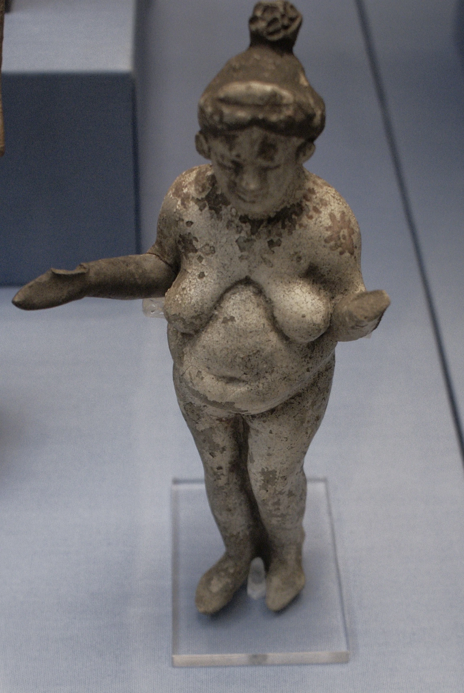 a stone statue of an ancient woman with two arms out