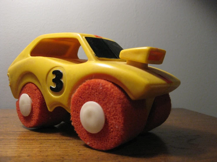 a yellow toy car sitting on top of a wooden table