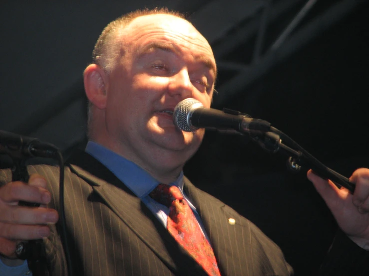 a man in a suit and tie is holding a microphone