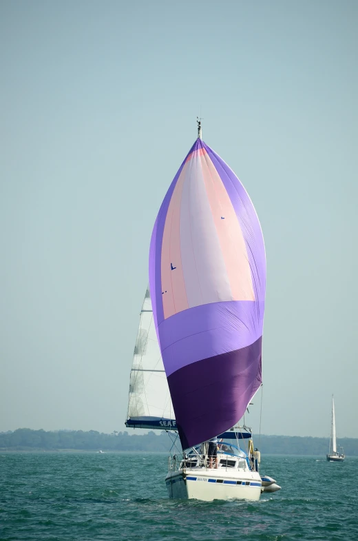 two colorful sailboats in a bay with one larger boat