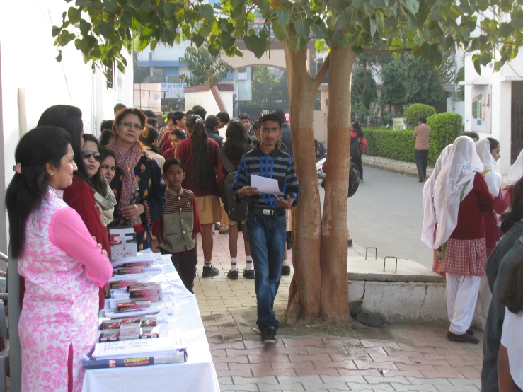 group of people on a sidewalk observing a table displaying brochures