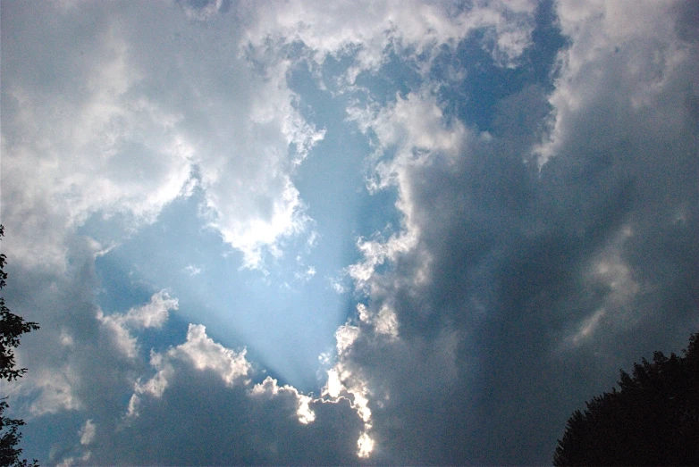 the sun coming through clouds in a blue sky