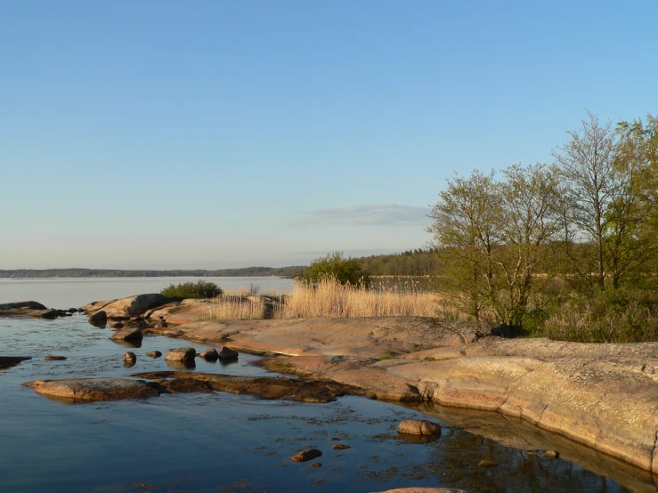 a water scene with rocks in the water and the sky in the background