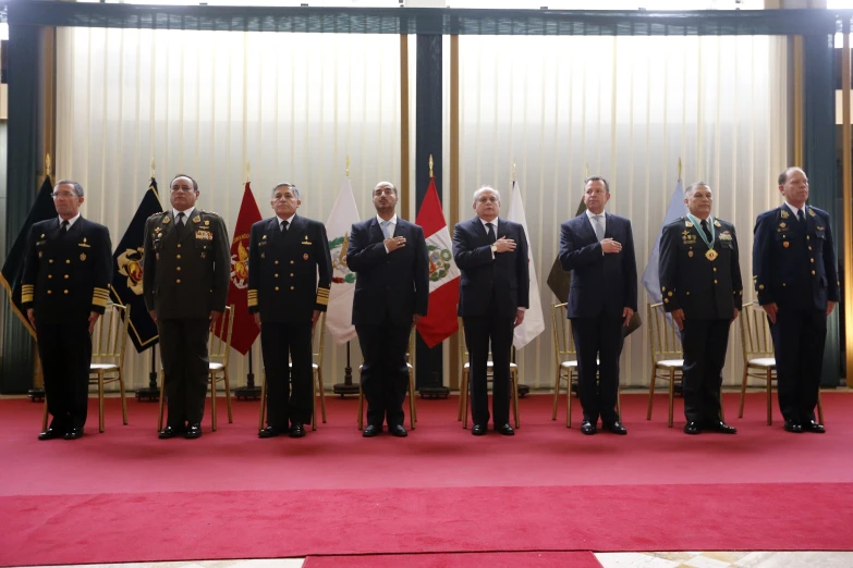 several men standing in uniform near flags at a ceremony