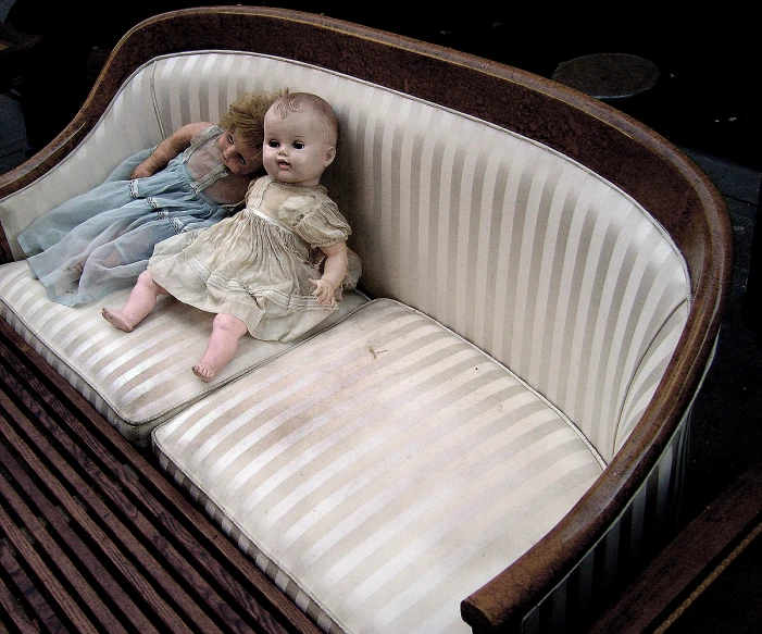 an antique baby crib is featured with two dolls