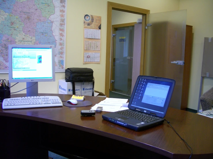 a laptop sits on a desk with a desktop computer